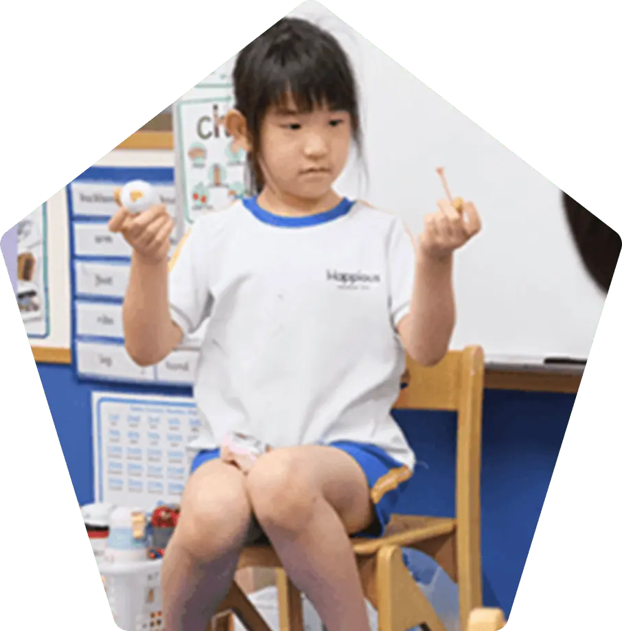 英語のアルファベット表の前で集中する子ども