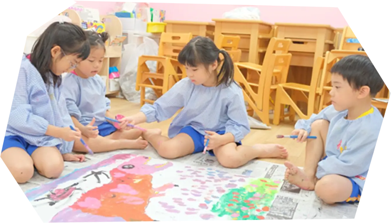 子どもたちが床に広げた絵を描いている様子